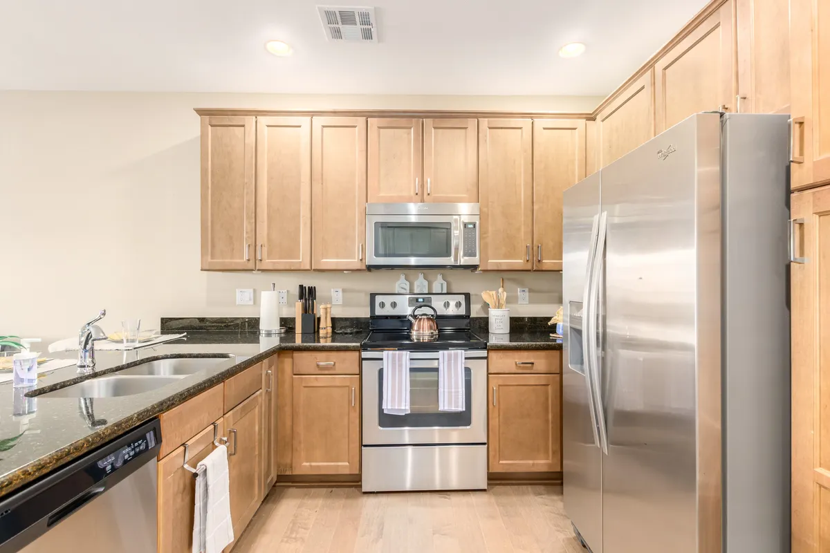 A modern clubhouse kitchen with stainless steel appliances, granite countertops, and warm wood cabinetry. The space is welcoming for entertaining, cooking, and hosting gatherings.