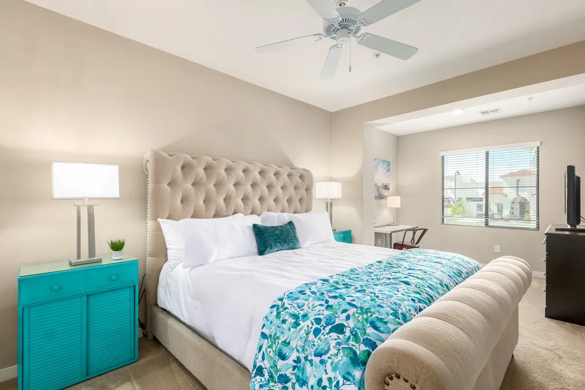 A tranquil bedroom setting features a tufted headboard, colorful bedding, and softly lit nightstands, evoking a sense of peaceful retreat and restful nights.