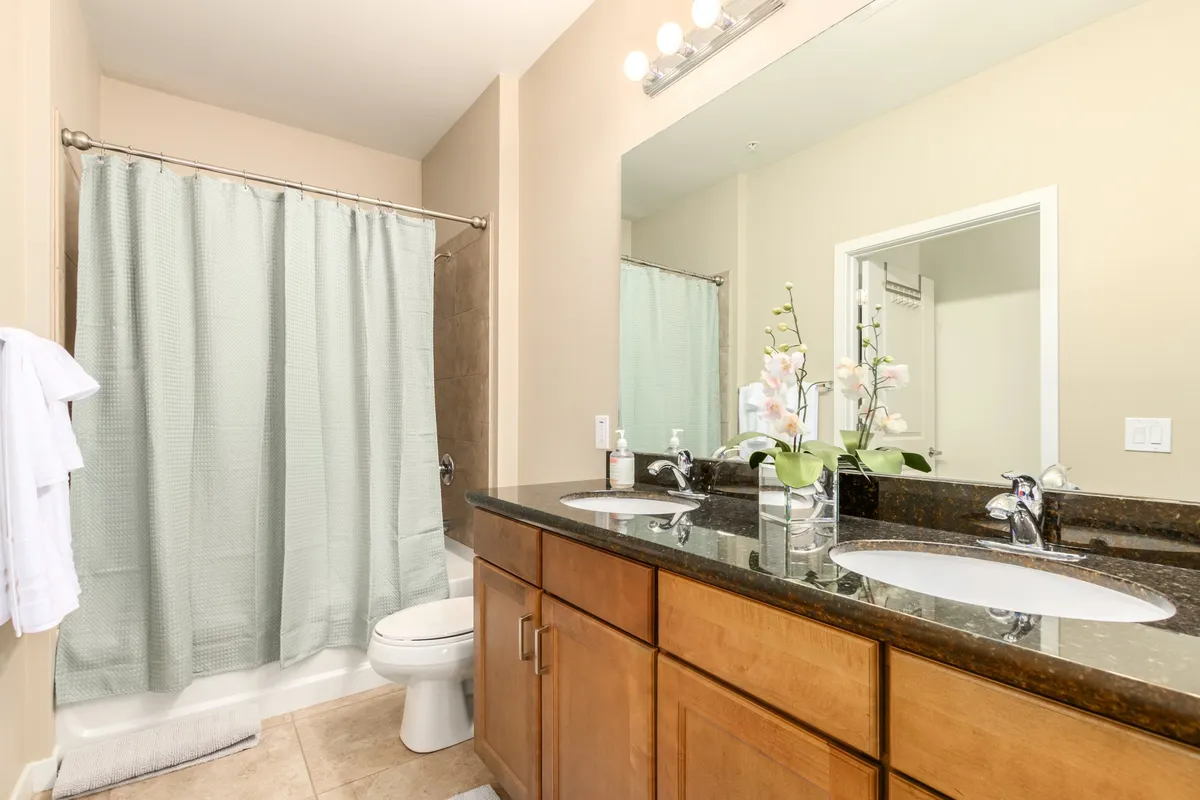 A serene bathroom featuring a double sink vanity, a spacious walk-in shower, and a decorative plant. The space exudes a spa-like atmosphere, perfect for self-care routines and relaxation after workouts or time at the pool.
